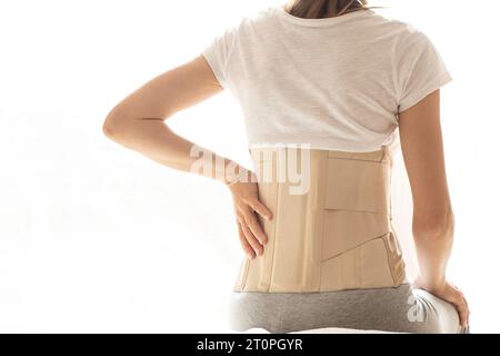 Femme avec un corset sur le dos pour soutenir son dos de la douleur dans le dos et la colonne vertébrale, concept médical, soutien spinal, mal de dos, portant une attelle à ho Banque D'Images