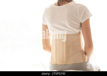 Femme avec un corset sur le dos pour soutenir son dos de la douleur dans le dos et la colonne vertébrale, concept médical, soutien spinal, mal de dos, portant une attelle à ho Banque D'Images