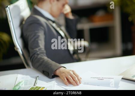 Nouveau travail. Gros plan sur la femme travailleuse moderne dans le bureau vert moderne en costume gris d'affaires avec lettre de licenciement d'employé. Banque D'Images