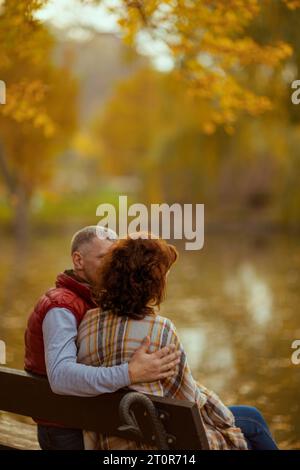 Bonjour automne. Vu de derrière la famille romantique dans le parc assis sur le banc. Banque D'Images