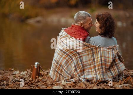 Bonjour automne. Vu de derrière couple moderne dans le parc avec couverture sertie. Banque D'Images