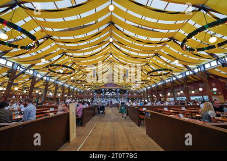 Munich, Allemagne, UE - 18 septembre 2023. À l'intérieur d'une tente de bière Oktoberfest pendant Oktoberfest 2023 avec des gens dans dirndls et lederhosen boire. Banque D'Images