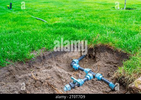 Auto-installation de l'irrigation avec un arroseur rétractable dans la pelouse finie. Pose de conduites d'eau avec des pulvérisateurs sous la pelouse pour l'irrigation. Banque D'Images