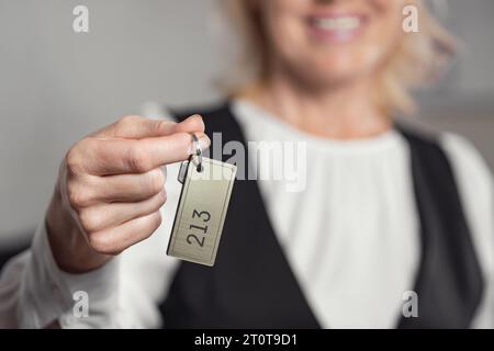 Gros plan de la clé de l'hôtel. Lady donne la clé de la chambre au client Banque D'Images