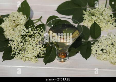 verre original avec liqueur de fleur de sureau avec décoration de fleurs âgées sur fond en bois Banque D'Images