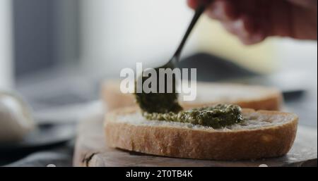 étalez le pesto sur une tranche de ciabatta fraîche pour faire un sandwich de gros plan, photo large Banque D'Images