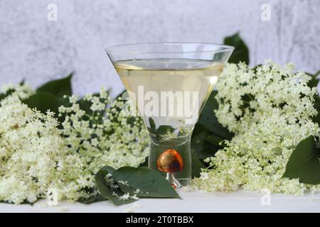 verre original avec liqueur de fleur de sureau avec décoration de fleurs âgées sur fond en bois Banque D'Images