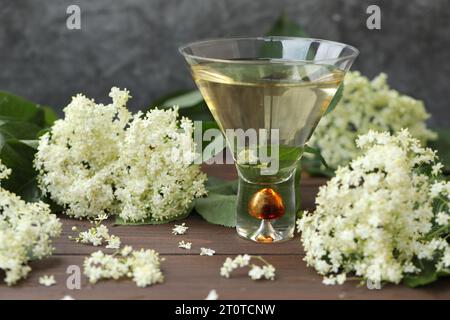 verre original avec liqueur de fleur de sureau avec décoration de fleurs âgées sur fond en bois Banque D'Images