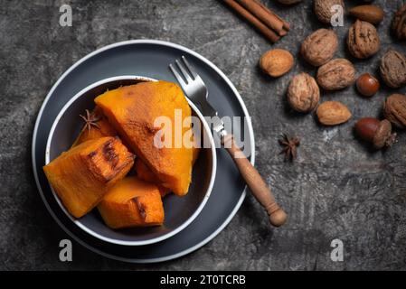 Citrouille fraîchement cuite dans un bol avec des noix sur un fond sombre. Aliments sains et biologiques Banque D'Images