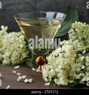 verre original avec liqueur de fleur de sureau avec décoration de fleurs âgées sur fond en bois Banque D'Images