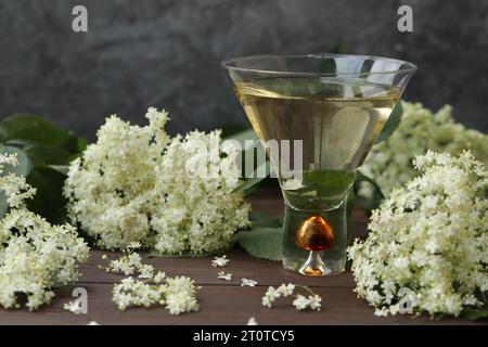 verre original avec liqueur de fleur de sureau avec décoration de fleurs âgées sur fond en bois Banque D'Images