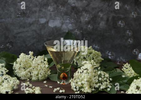 verre original avec liqueur de fleur de sureau avec décoration de fleurs âgées sur fond en bois Banque D'Images