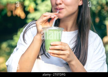 Femme élégante buvant du matcha latte dans le parc. Banque D'Images