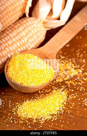 Polenta de farine de maïs dans un bol en bois et épis de maïs secs isolés sur fond blanc. Banque D'Images