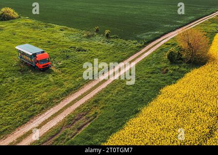 Prise de vue aérienne d'un camion d'apiculture avec des caisses en bois de ruche colorées dans une remorque, drone pov Banque D'Images