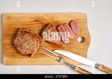 Vue de dessus de steak de bœuf juteux moyen rare sur planche à découper en bois coupé sur tranches Banque D'Images