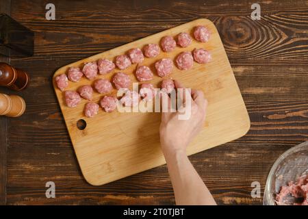 Vue de dessus de la main femelle mettant la boulette de viande sur une planche dans une rangée Banque D'Images