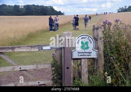 Les gens marchent devant le panneau du National Trust et la porte en bois sur le chemin de Stonehenge depuis le Visitor Exhibition Centre sur la plaine de Salisbury, Wiltshire, Angleterre Banque D'Images