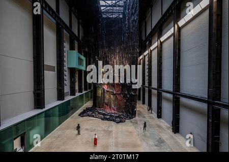 Londres, Royaume-Uni. 9 octobre 2023. Hyundai Commission : El Anatsui : derrière la Lune Rouge dans la turbine Hall de la Tate Modern. Les images NE DOIVENT être utilisées QUE pour référencer cette installation. El Anatsui, né au Ghana et basé au Nigeria, est surtout connu pour ses sculptures métalliques en cascade construites avec des milliers de bouchons de bouteilles recyclés articulés avec du fil de cuivre. Réutilisant les matériaux trouvés en œuvres éblouissantes d'art abstrait, le travail d'Anatsui explore des thèmes qui incluent l'environnement, la consommation et le commerce. Crédit : Guy Bell/Alamy Live News Banque D'Images