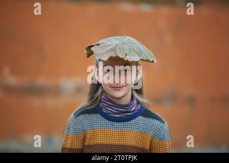 fille souriante avec feuille d'automne sur sa tête Banque D'Images