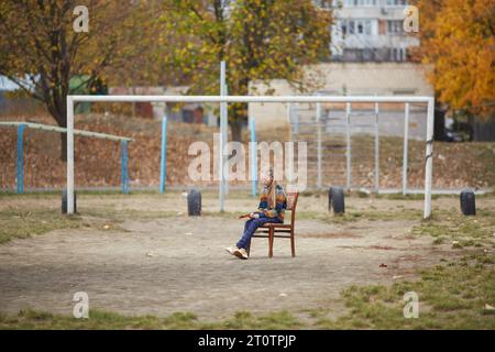 fille calme assise sur une chaise sur le terrain de sport Banque D'Images