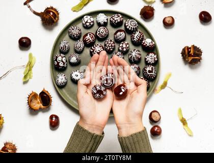 Belles châtaignes peintes à la main avec différents motifs tiennent par les mains. Concept d'artisanat pour enfants amusant et facile. Tutoriel étape par étape. Banque D'Images