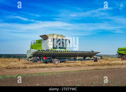 Champ d'automne avec récolteuse sur fond de ciel. La récolteuse agricole recueille la récolte dans le champ Banque D'Images