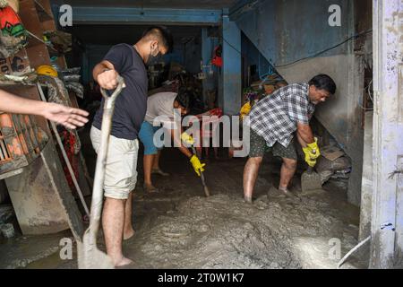 Singtam, Inde. 09 octobre 2023. Sanjay Prasad (à droite) et ses fils retirent le limon et la boue de leur magasin dans la zone touchée par les inondations le long de la rivière Teesta. Après qu’un lac glaciaire dans le nord-est de l’Inde ait traversé un barrage peu après minuit, emportant des maisons et des ponts et forçant des milliers de personnes à fuir, les sauveteurs ont continué à creuser à travers des débris boueux. Crédit : SOPA Images Limited/Alamy Live News Banque D'Images