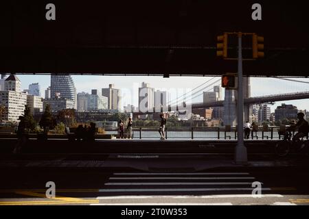NEW YORK, États-Unis - 26 NOVEMBRE 2022 : personnes sur le remblai de la rivière est avec vue sur le pont de manhattan Banque D'Images