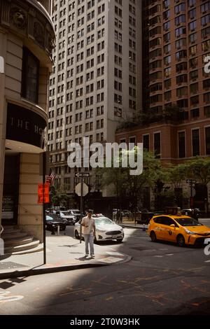 NEW YORK, États-Unis - 26 NOVEMBRE 2022 : Homme marchant sur le trottoir près d'un carrefour avec des voitures en mouvement Banque D'Images