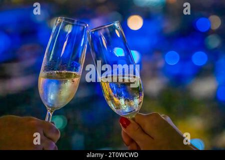 Deux personnes grillant avec des verres de champagne contre la vue sur la ville la nuit Banque D'Images