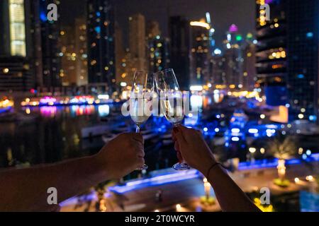 Deux personnes grillant avec des verres de champagne contre la vue sur la ville la nuit Banque D'Images