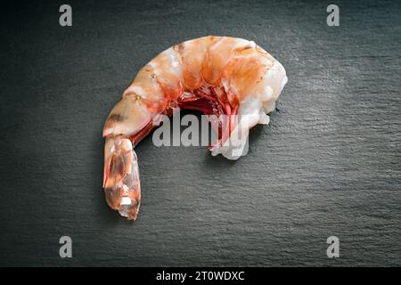 Crevette géante géante fraîche crue avec coquille sans tête, nettoyée et prête à cuire sur une assiette d'ardoise sombre, vue de dessus, espace de copie, foc sélectionné Banque D'Images