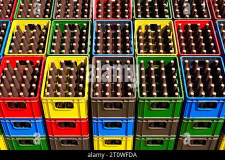 D'innombrables caisses de bière colorées pleines de bouteilles empilées dans un entrepôt extérieur. Banque D'Images