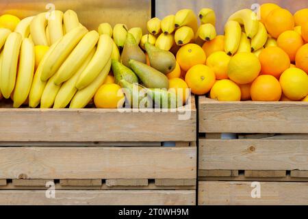 Étal de marché avec des bananes fraîches, des poires et des oranges dans des caisses en bois Banque D'Images