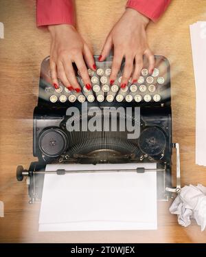 Vue de dessus les mains de femme tapant sur la machine à écrire vintage. Style rétro et concept de travail. Gros plan Banque D'Images