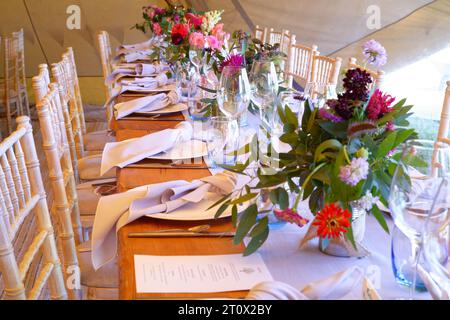 Chapiteau de mariage décoré et prêt pour les invités à arriver. Tables, chaises, fleurs et décors. Une conception rustique de tipi de tente. Banque D'Images