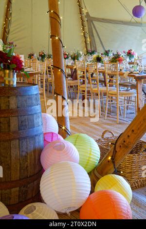 Chapiteau de mariage décoré et prêt pour les invités à arriver. Tables, chaises, fleurs et décors. Une conception rustique de tipi de tente. Banque D'Images