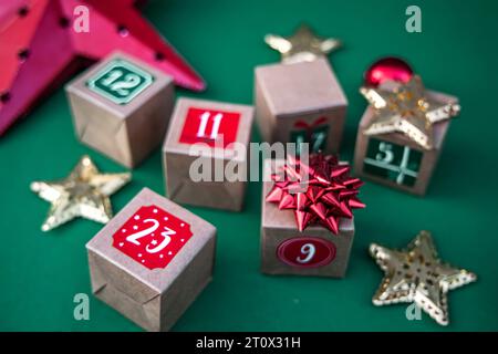 Calendrier de l'Avent artisanal : cubes de papier kraft avec des chiffres sur un fond vert vibrant. Adoptez la tradition des fêtes Banque D'Images