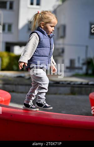 Petite fille, 2 ans, blonde, équilibrante, jouant, aire de jeux, Stuttgart, Baden-Wuerttemberg, Allemagne Banque D'Images