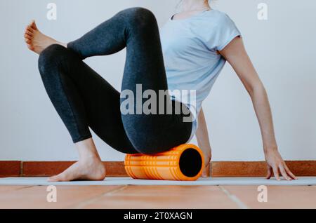 Femme faisant le relâchement myofascial fessier sur rouleau de mousse Banque D'Images