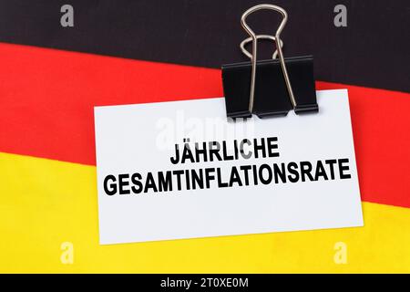 Concept d'économie et de finance. Sur le drapeau de l'Allemagne se trouve une carte de visite avec l'inscription - taux annuel d'inflation global. Texte en allemand. Banque D'Images