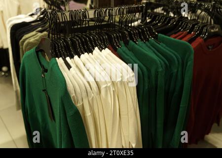 Les pulls pour hommes sont accrochés à des cintres dans un magasin de vêtements. Gros plan, arrière-plan. Netteté sélective. Banque D'Images