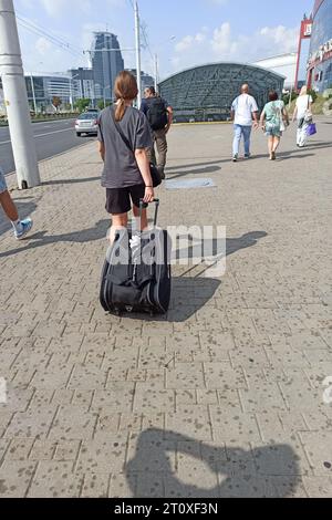 Biélorussie, Minsk - 20 septembre 2023 : fille avec un sac sur roues sur le trottoir Banque D'Images