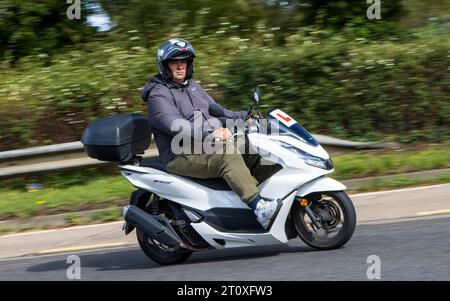 Milton Keynes, Royaume-Uni - 21 septembre 2023 : Homme conduisant un scooter blanc Honda PCX sur une route anglaise Banque D'Images