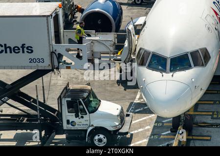 Aéroport JFK, NY, États-Unis - 11 juillet 2023 ; gros plan d'un membre du personnel au sol poussant un chariot de restauration dans un avion Delta depuis un camion de restauration de l'aéroport Banque D'Images