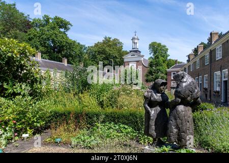 Breda, pays-Bas-18 juillet 2023 ; Statue de deux béguines dans la cour du béguinage (Begijnhof) avec jardin d'herbes aromatiques et entouré de 29 petits Banque D'Images