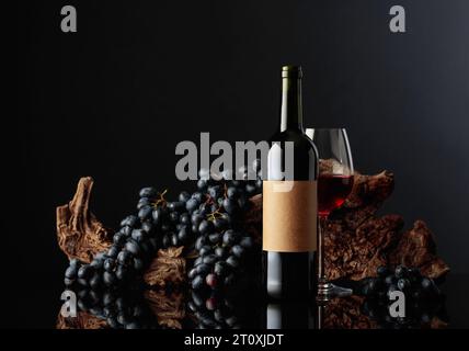 Bouteille de vin rouge avec vieille étiquette vide. En arrière-plan, de vieux accrochages altérés et des raisins bleus. Banque D'Images