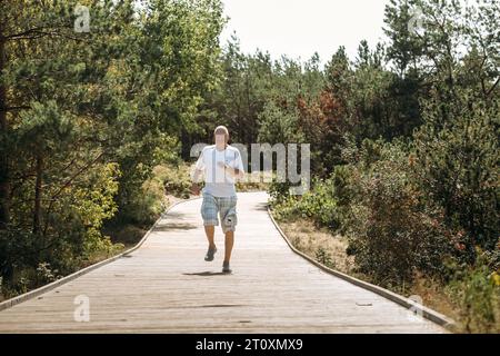 Un homme âgé joyeux court le long d'un chemin dans un parc. Banque D'Images