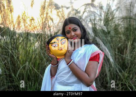 La mannequin Rima Bhattacharya pose en portant un saree indien traditionnel et tenant un visage d'argile d'idole Durga pendant la séance photo en plein air Agomoni concept dans une zone remplie de chatons ou de cachous à environ 60 km de Kolkata. Le mannequin Rima Bhattacharya pose pour une photo pour la série photo basée sur le thème de Durga Puja Vibes en Inde. Rima Bhattacharya, mannequin de mode et célébrité dans l'industrie de la mode et de la télévision bengali collabore avec la série photo pour promouvoir Durga Puja. La série photo est organisée par un groupe de photographes visant à documenter et promouvoir la pré- Banque D'Images